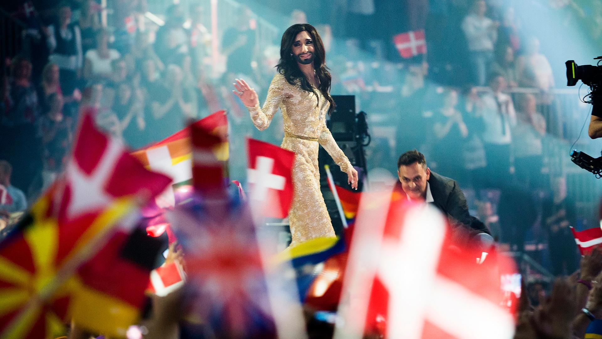 Beim 59. Eurovision Song Contest (ESC)  in Kopenhagen 2014 lässt sich Conchita Wurst nach dem Sieg auf der Bühne feiern, im Vordergrund sind Flaggen verschiedener Länder zu sehen.
