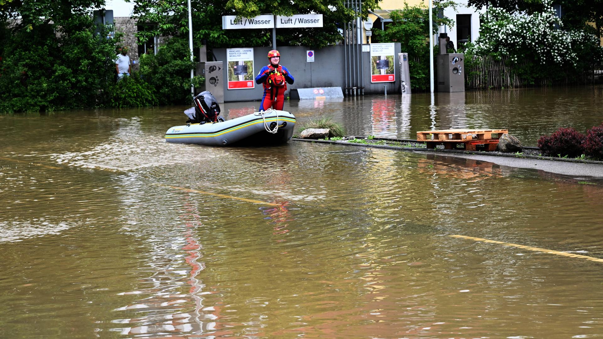 Das Bild zeigt einen Helfer in einem Schlauchboot bei einer überschwemmten Tankstelle in Allershausen in Bayern. 