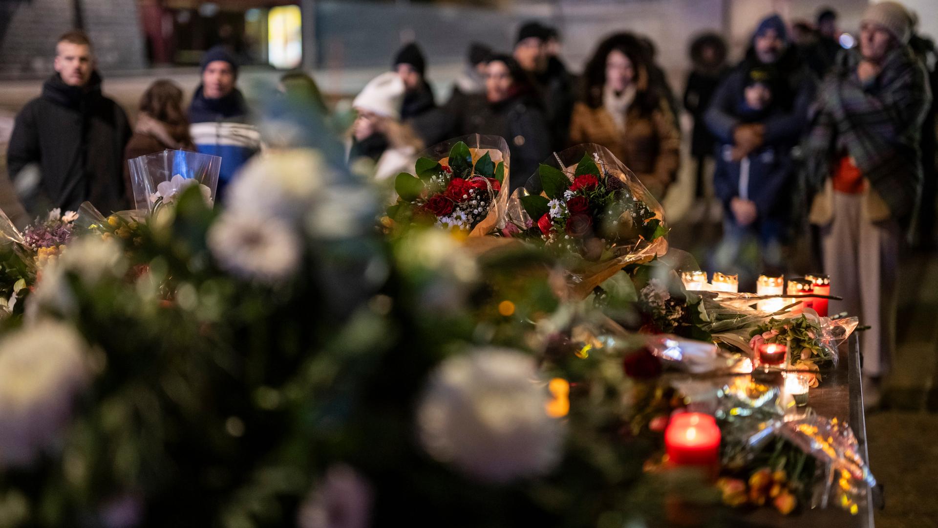 Crans-Montana: Menschen legen Blumen vor der Bar ab, in der das Feuer ausbrach, und zünden Kerzen für die Opfer an. 