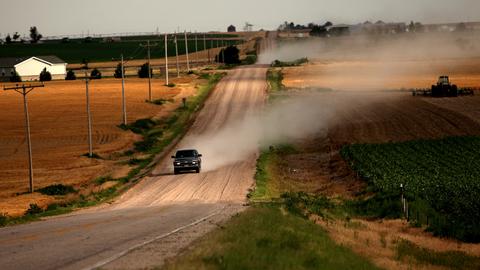 Ein einsamer Pickup Truck fährt eine ländliche Straße im US-Bundesstaat Colorado entlang und wirbelt eine Staubwolke auf.