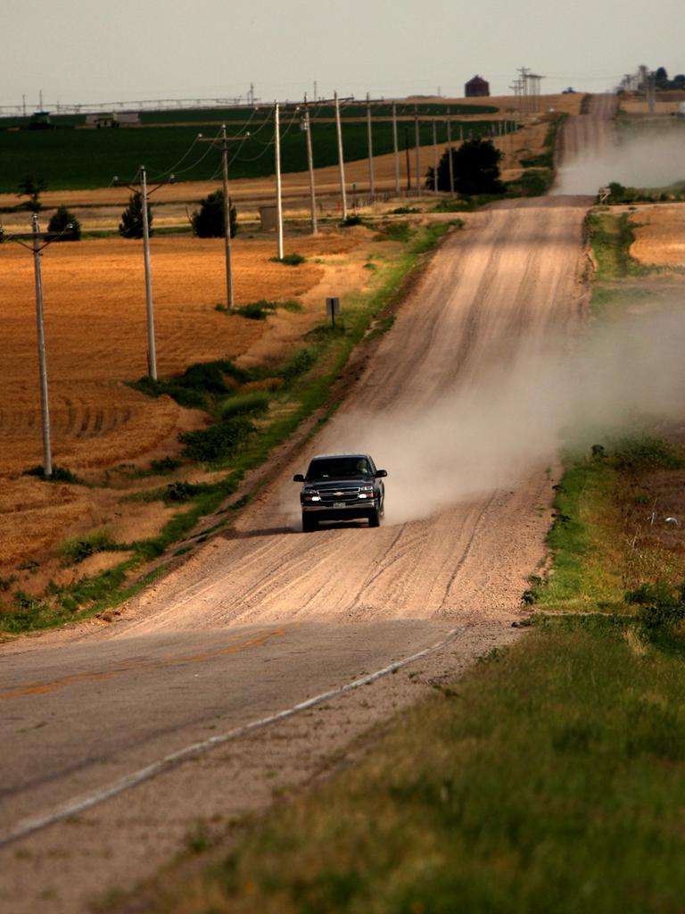 Ein einsamer Pickup Truck fährt eine ländliche Straße im US-Bundesstaat Colorado entlang und wirbelt eine Staubwolke auf.
