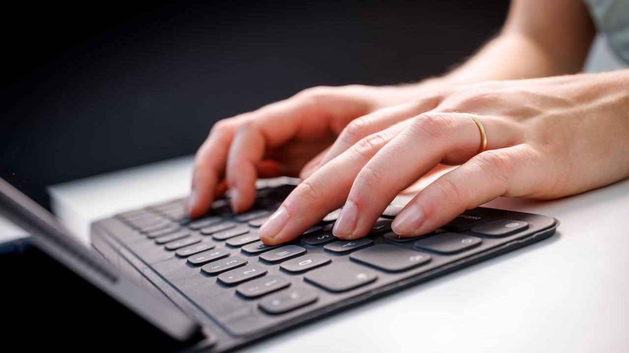 Hände tippen auf einem Tablet mit Tastatur.