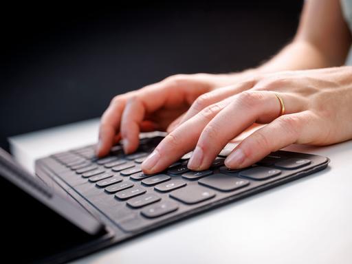 Hände tippen auf einem Tablet mit Tastatur