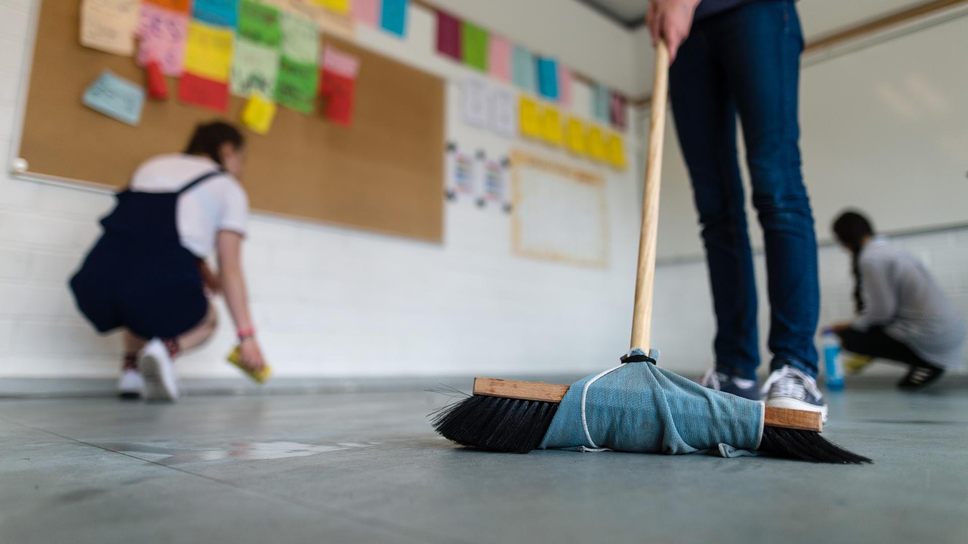 Schüler wischen und putzen ihre Klasse. 