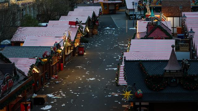 Mehrere Buden mit Weihnachts-Schmuck stehen auf einem Platz. Auf dem Boden liegen Papiere und ein umgestürzter Tisch.