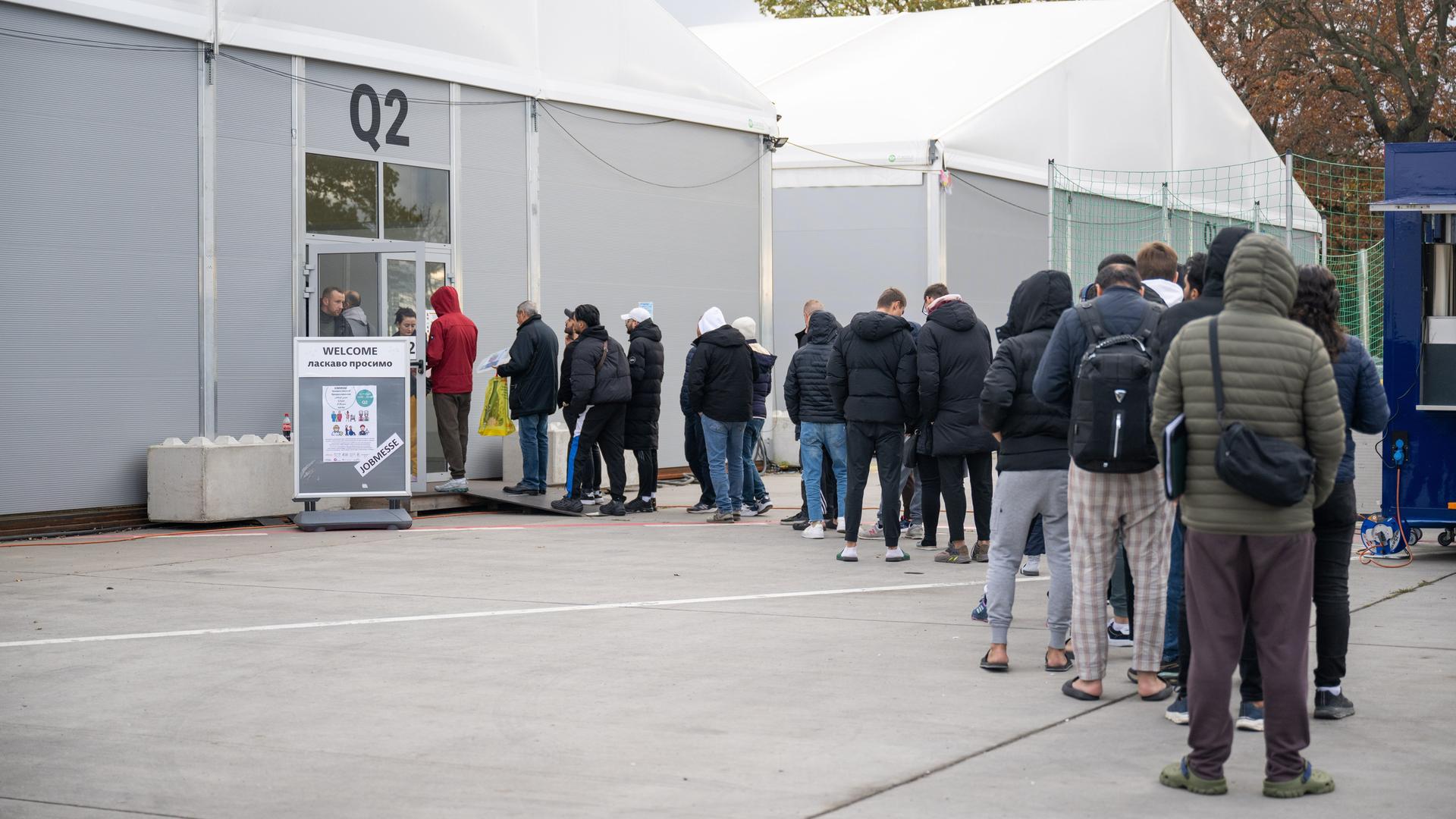 Berlin: Am ehemaligen Flughafen Tegel stehen Geflüchtete Menschen vor einer Leichtbauhalle. 