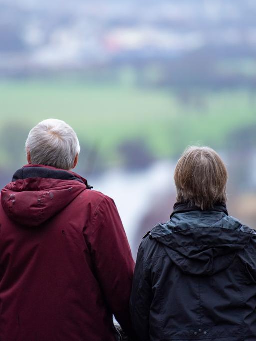 Ein Mann und eine Frau stehen auf einer Aussichtsplattform und schauen auf einen Fluss und eine Landschaft.