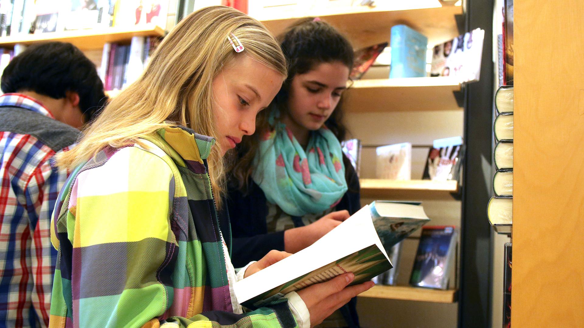 Zwei Mädchen blättern in einer Buchhandlung in Büchern.