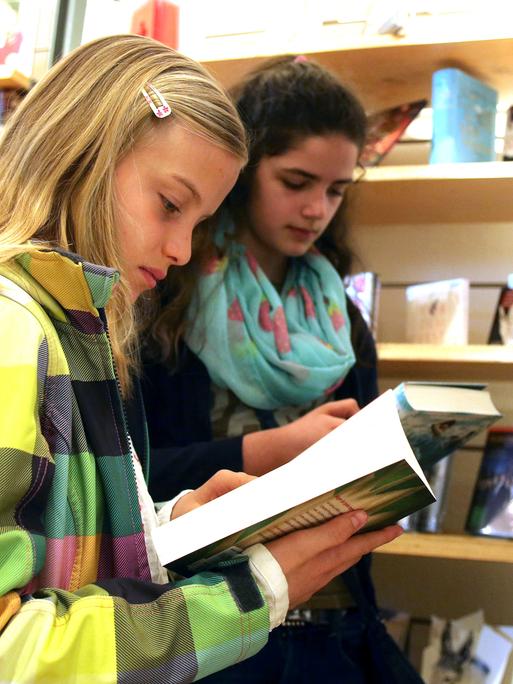 Zwei Mädchen blättern in einer Buchhandlung in Büchern.