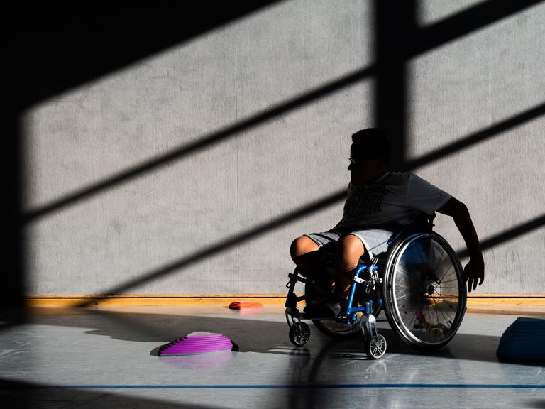 Ein Schüler einer Förderschule fährt in der Sporthalle des Gymnasium Burgdorf mit seinem Rollstuhl Slalom um Hindernisse. 