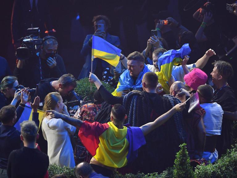 Die Band Kalush Orchestra aus der Ukraine feiert nach dem Sieg beim Eurovision Song Contest 2022. Ukrainische Fahnen werden geschwenkt, es wird gefilmt und fotografiert.  