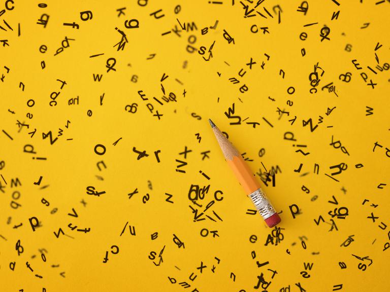Illustration: Auf einem gelben Hintergrund ist ein Bleistift zwischen zahlreichen ungeordneten Buchstaben zu sehen. 