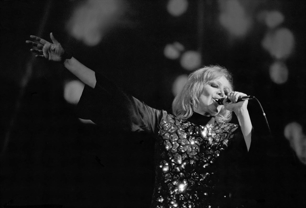 Schwarzweißbild: Eine Frau hebt mit großen Gestus den Arm, singt innig in ein Mikrofon. Hildegard Knef während eines Konzerts in der Berliner Philharmonie 1980.