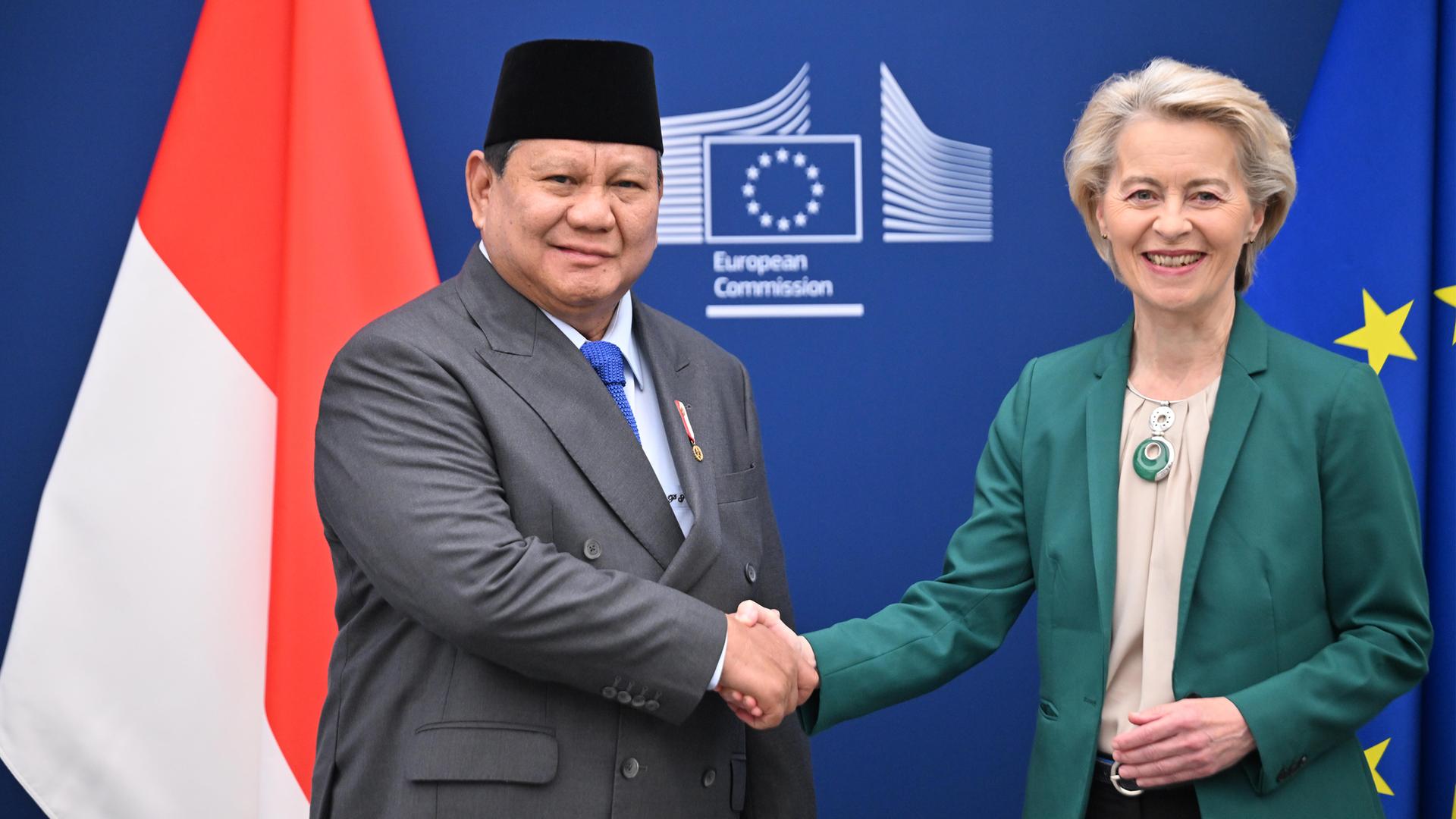 Prabowo Subianto, Präsident von Indonesien, und EU-Kommissionspräsidentin Ursula von der Leyen schütteln Hände vor einer Wand mit dem Logo der EU-Kommission sowie den Flaggen Indonesiens und der EU.