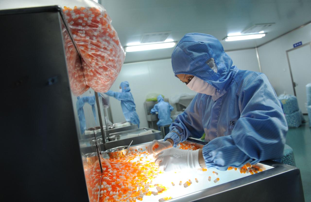 Eine Frau arbeitet in Schutzkleidung in einer Pharmafabrik in Xinchang, China.