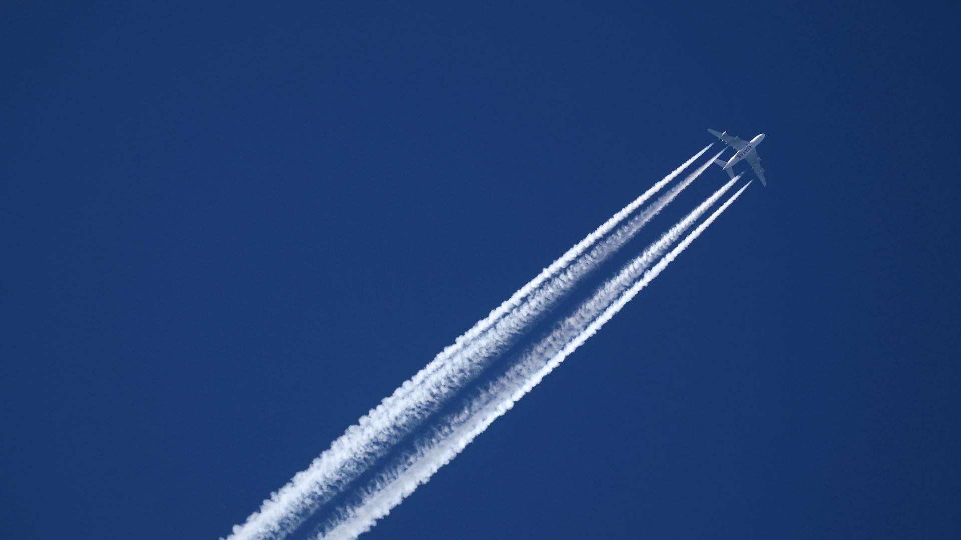 Ein Flugzeug der Qatar Airline hinterlässt am wolkenlosen Himmel Kondensstreifen.