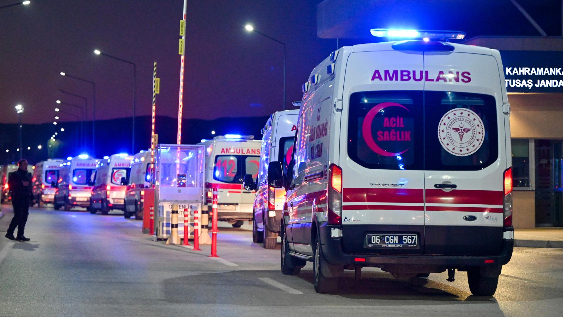 Es ist dunkel. Das Bild zeigt eine lange Reihe von Rettungswagen auf einer Straße; sie sind von hinten zu sehen. Auf dem Heck steht jeweils "Abulans"