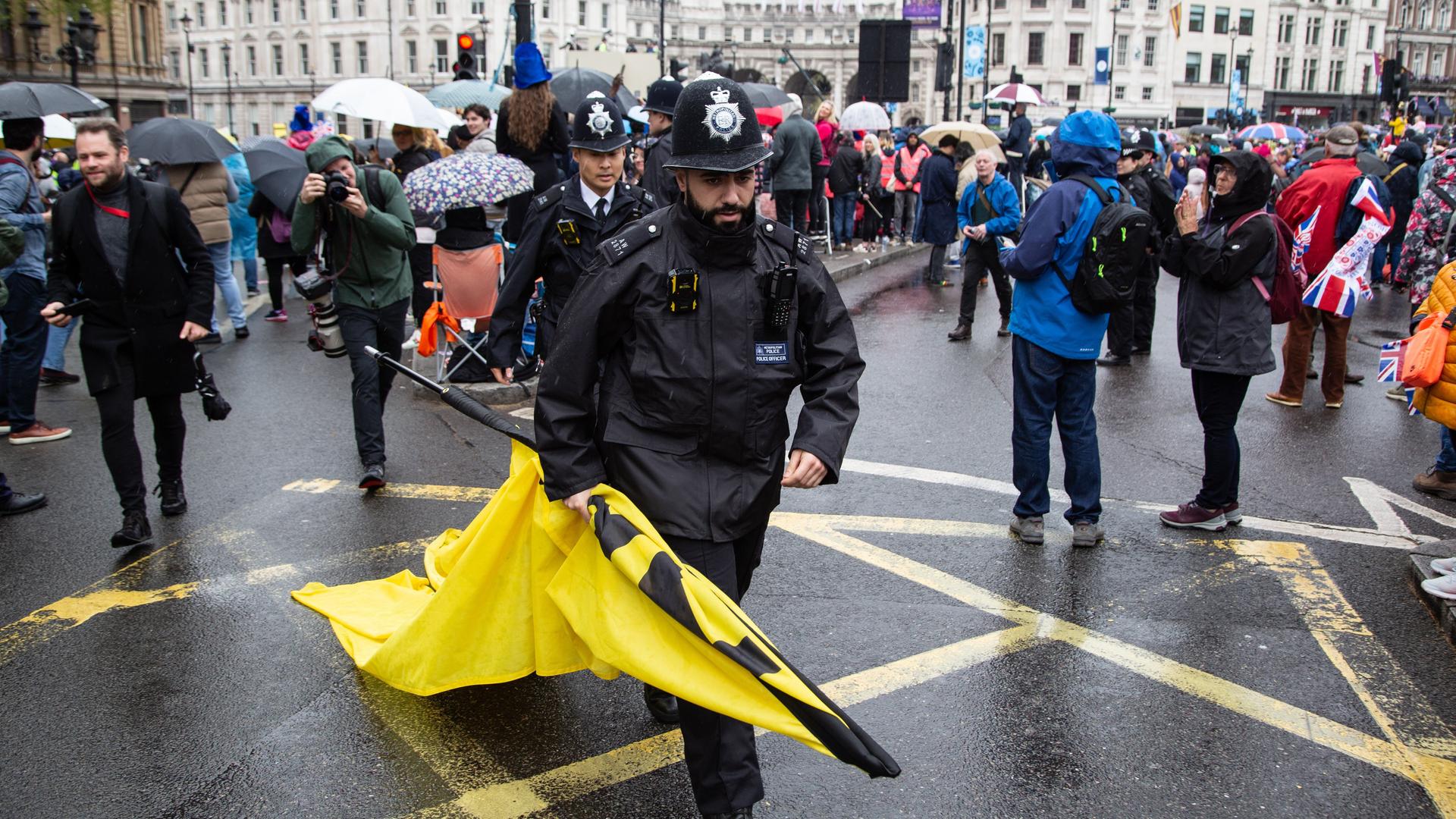 Ein Polizist trägt ein Banner davon, das während anti-monarchistischer Proteste zur Krönung von König Charles III. in London sichergestellt wurde. Ein Polizist trägt ein Banner davon, das während anti-monarchistischer Proteste zur Krönung von König Charles III. in London sichergestellt wurde.