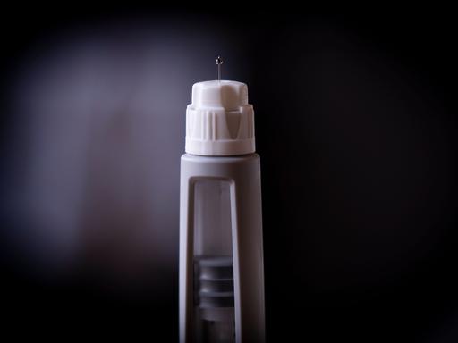 Aus einer Ozempic-Spritze kommt einer kleiner Tropfen. Die Spritze erinnnert an eine Rakete, die abhebt.