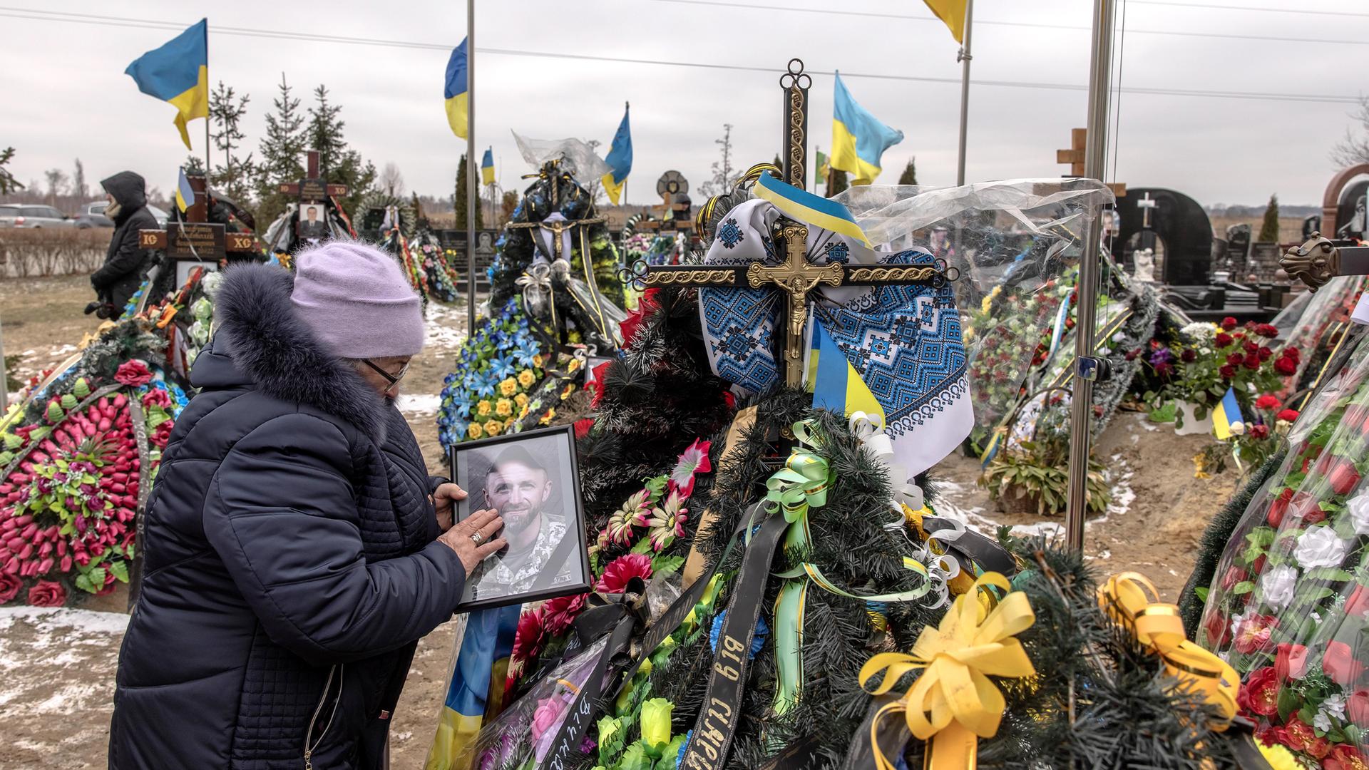 Maria, die Mutter des in Bakhmut getöteten ukrainischen Soldaten Vasyl Kurbyt, trauert an seinem Grab auf einem Friedhof, sie streichelt sein Foto. Am 24. Februar 2023, als die Ukraine den Jahrestag der russischen Invasion begeht.