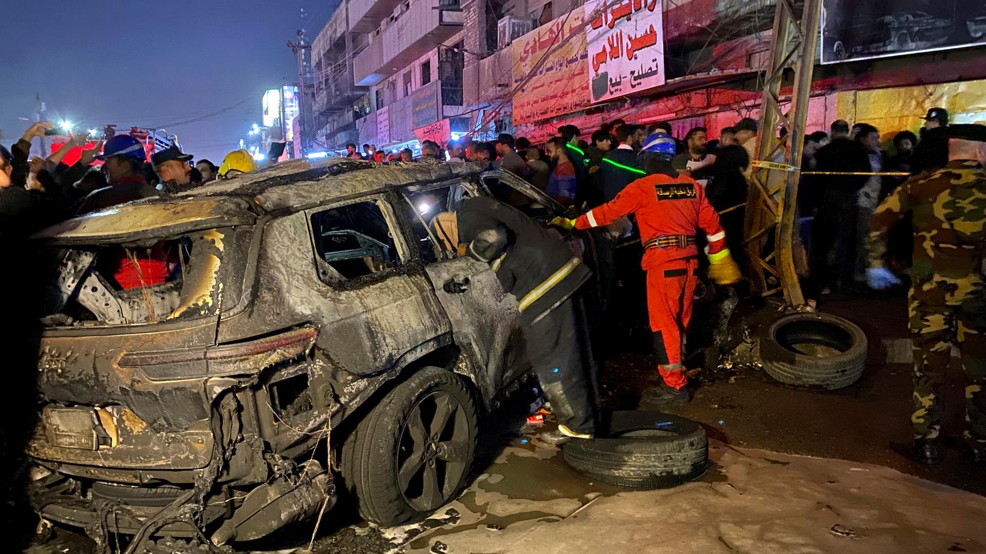 Auf einer Straße in Bagdad steht ein ausgebranntes Auto. 