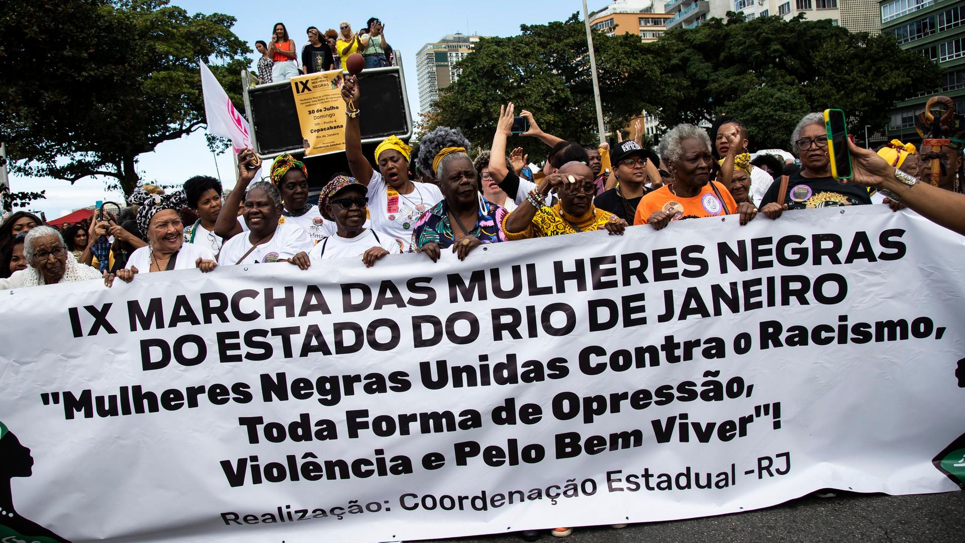Brasilien, Rio de Janeiro: Viele Afrobrasilianerinnen halten ein Banner in der Hand. Sie protestieren gegen Rassismus.