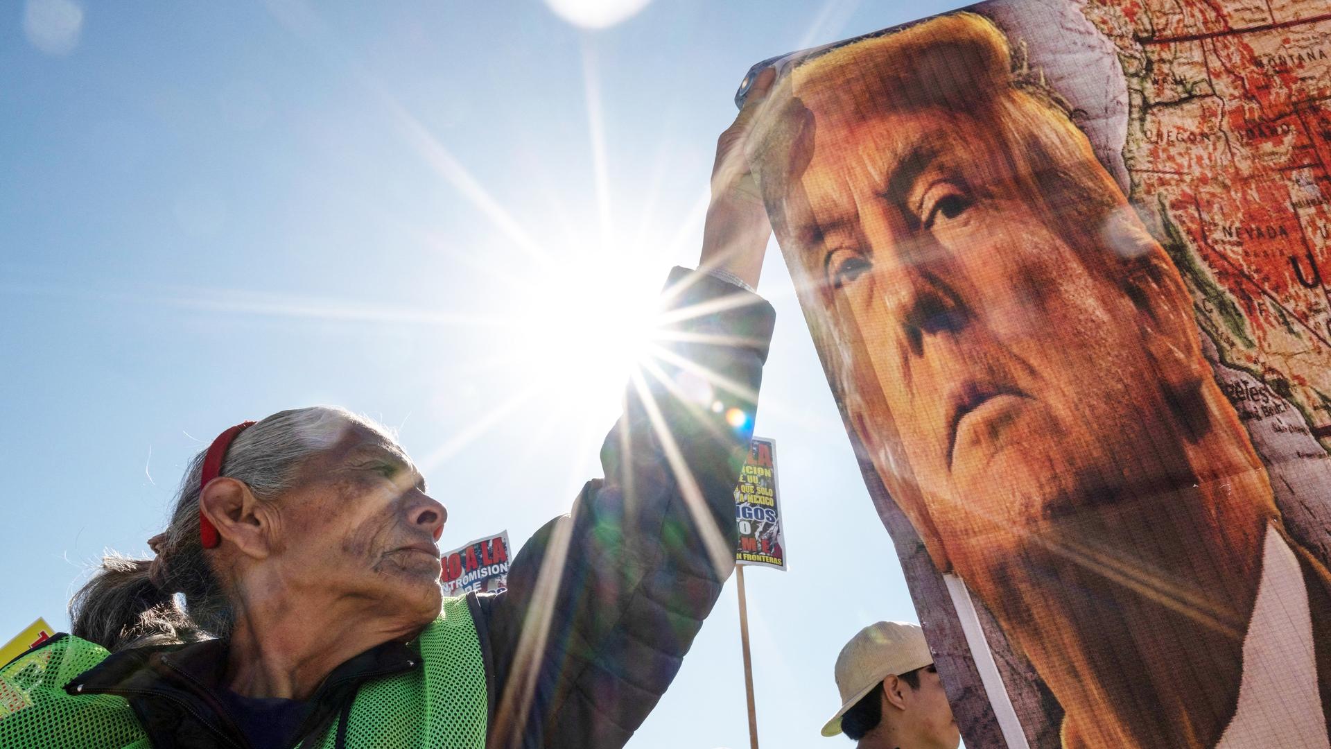 Eine Demonstrantin hält ein Protest-Transparent mit dem Bild des US-Präsidenten Donald Trump an dem Internationalen Tag der Migranten, an der Grenze zwischen den USA und Mexiko, Dezember 2024.