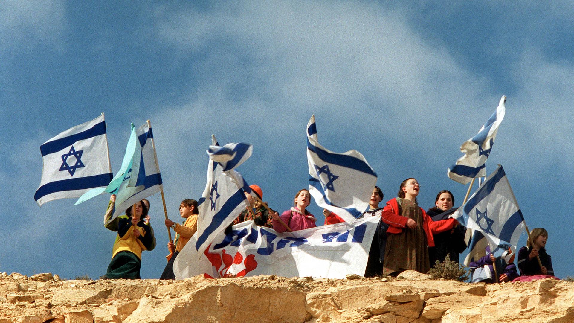 Junge jüdische Siedler schwenken israelische Flaggen auf einem Hügel in der Nähe einer illegalen Siedlung in der Westbank.