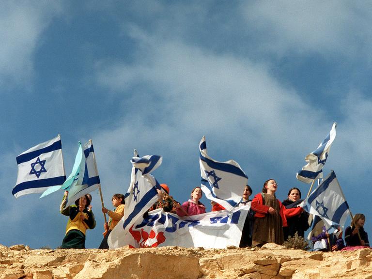 Junge jüdische Siedler schwenken israelische Flaggen auf einem Hügel in der Nähe einer illegalen Siedlung in der Westbank.