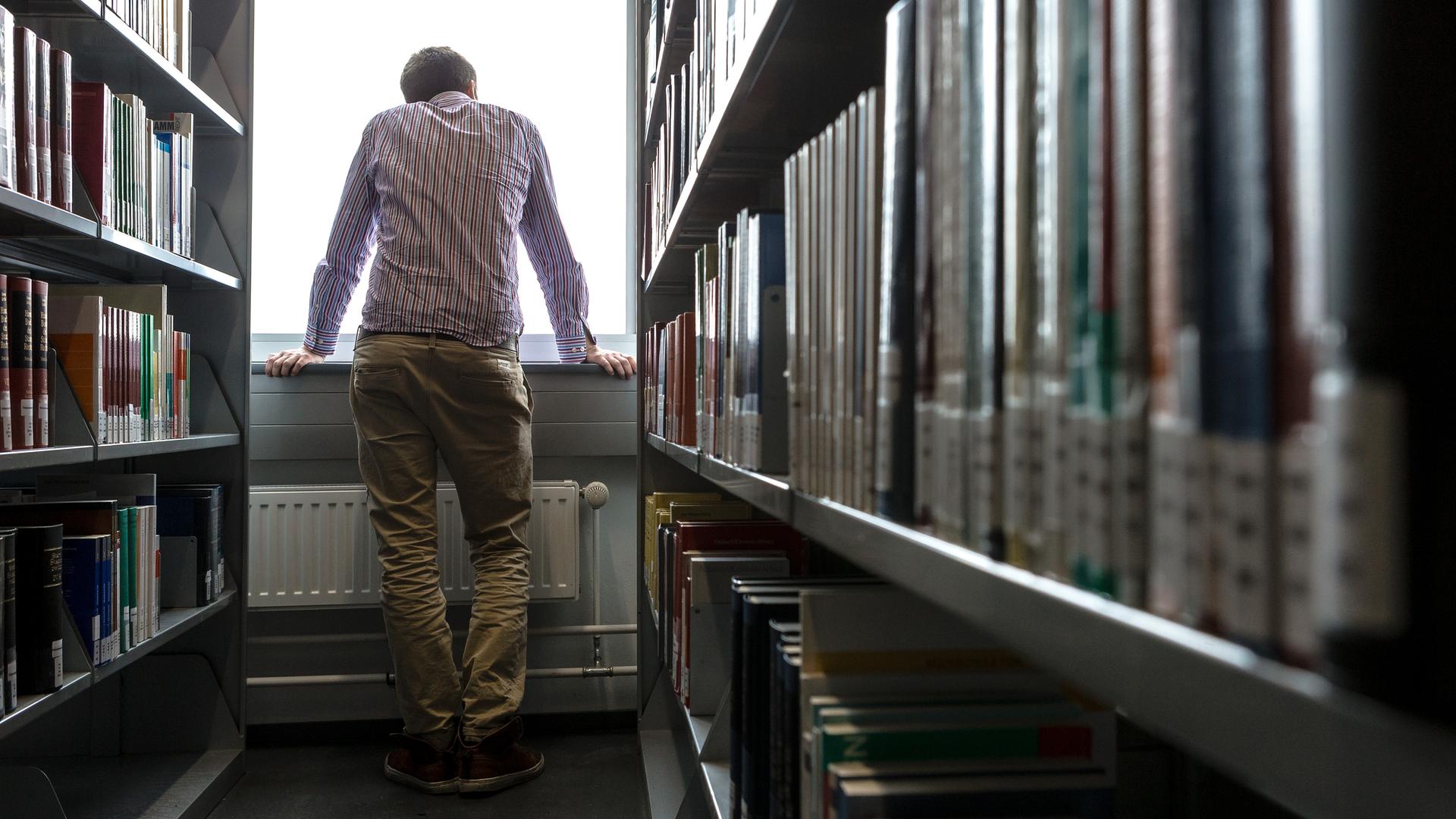 Ein Student schaut in einer Unibibliothek in Hamburg aus dem Fenster.