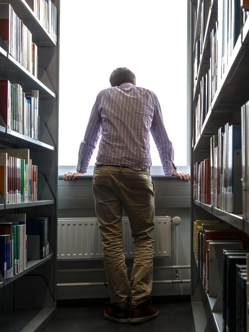 Ein Student schaut in einer Unibibliothek in Hamburg aus dem Fenster.