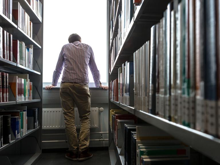 Ein Student schaut in einer Unibibliothek in Hamburg aus dem Fenster.