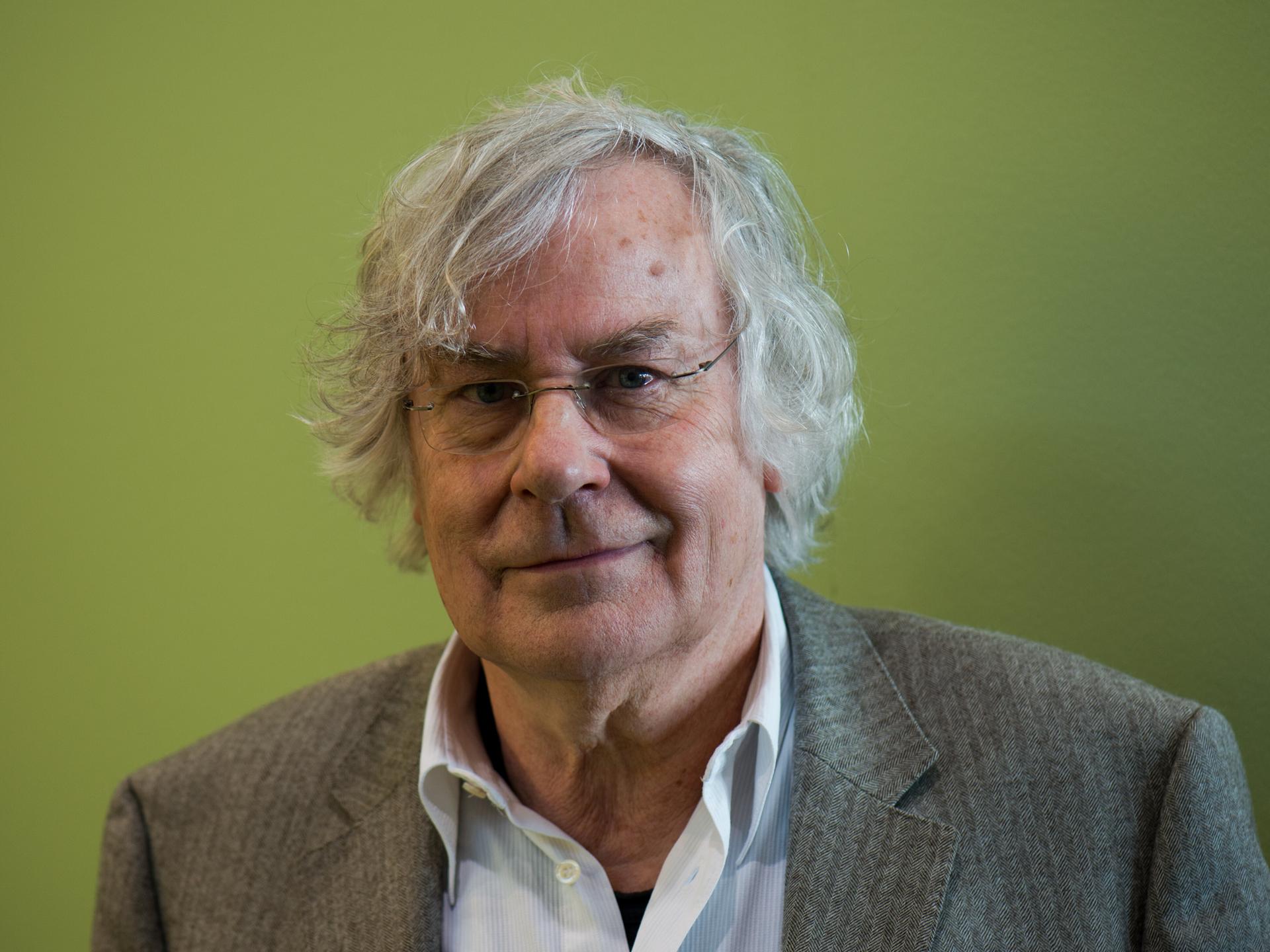 Helmut Lethen posiert in Sakko und offenem Hemd vor grünem Hintergrund für ein Porträt. Helmut Lethen posiert in Sakko und offenem Hemd vor grünem Hintergrund für ein Porträt.