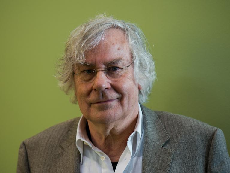 Helmut Lethen posiert in Sakko und offenem Hemd vor grünem Hintergrund für ein Porträt. Helmut Lethen posiert in Sakko und offenem Hemd vor grünem Hintergrund für ein Porträt.