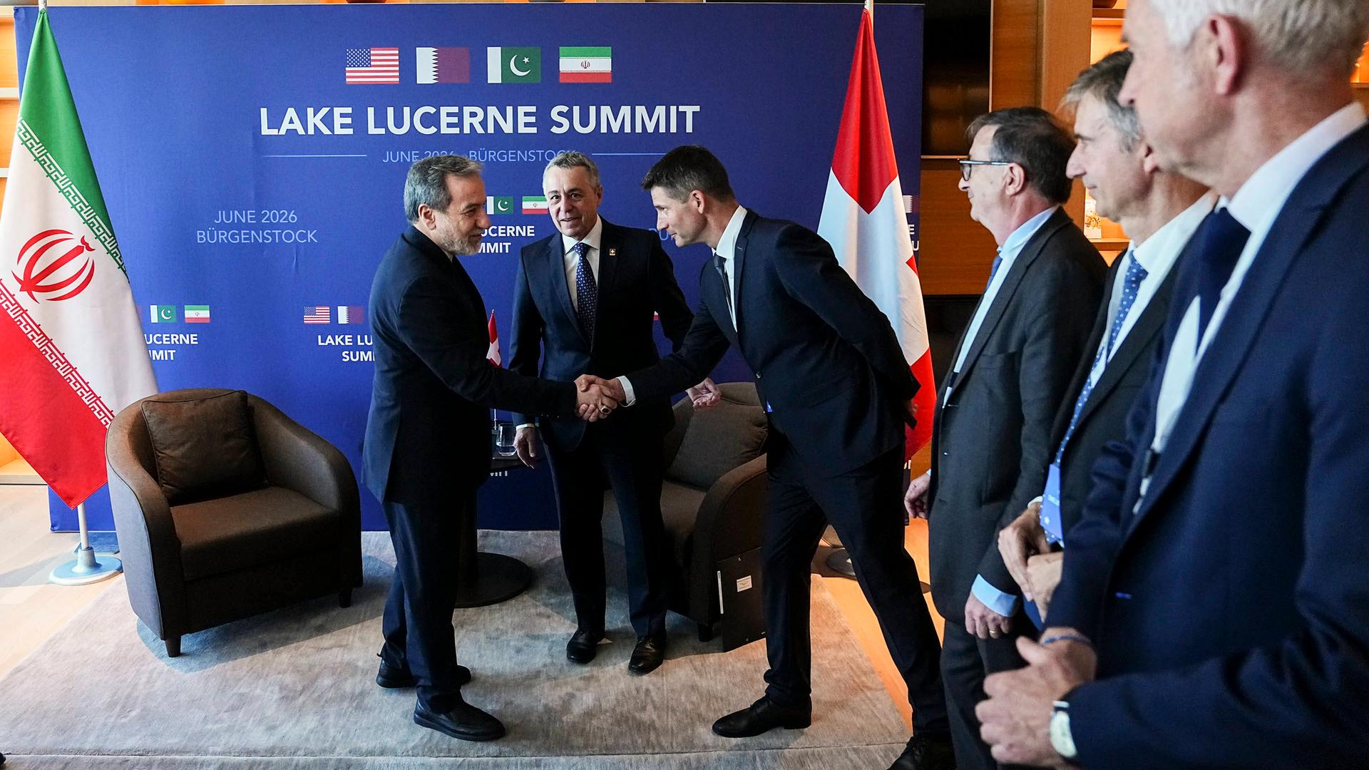 Der iranische Außenminister Araghtschi schüttelt einem Mann in einem Konferenzsaal die Hand.