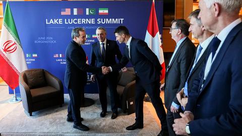 Der iranische Außenminister Araghtschi schüttelt einem Mann in einem Konferenzsaal die Hand.