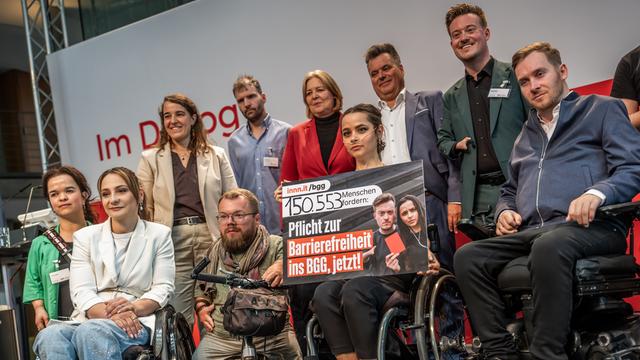 Politikerinnen, Politiker, Aktivistinnen und Aktivisten sind als Gruppe für ein Foto zusammen und lächeln.