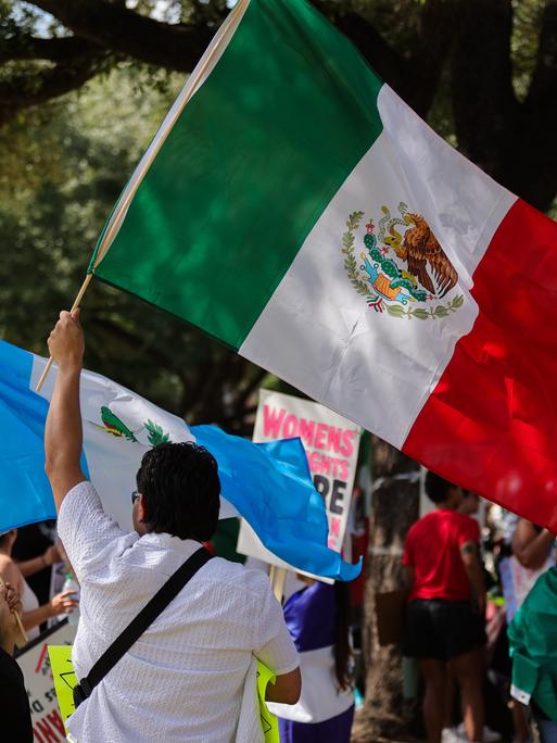 Demonstranten versammeln sich am 8. Juni 2025 im Ervan Chew Park in Houston, Texas, zu einer Demonstration gegen Trumps Einwanderungspolitik und Massenabschiebungen. Ein Demonstrant schwenkt die mexikanische Flagge.