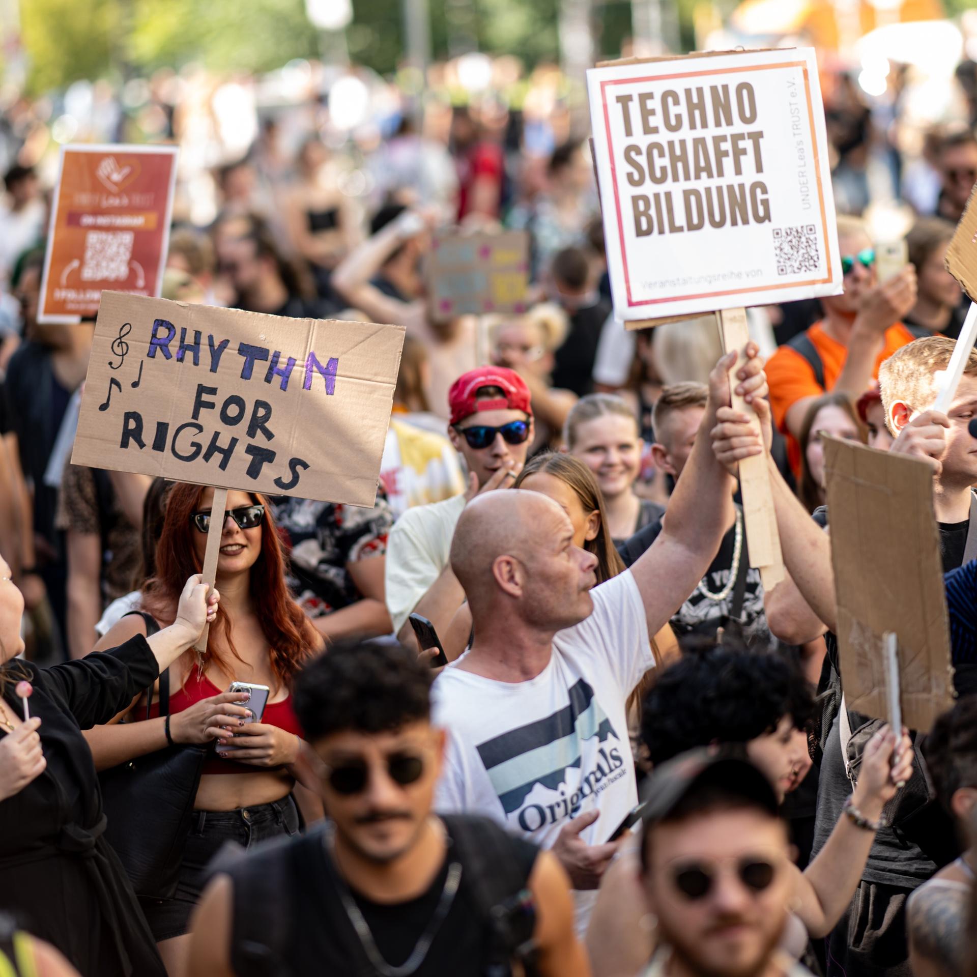 Viele Menschen nehmen an der Technoparade "Zug der Liebe" - Demonstration für Toleranz, Vielfalt und Miteinander mit Schildern mit der Aufschrift "Rythm for Rights" und "Techno schafft Bildung" teil.