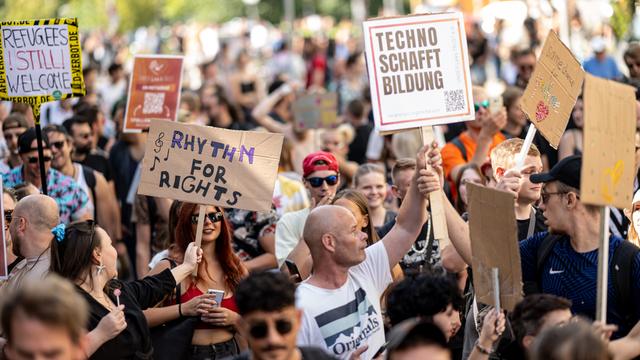 Viele Menschen nehmen an der Technoparade "Zug der Liebe" - Demonstration für Toleranz, Vielfalt und Miteinander mit Schildern mit der Aufschrift "Rythm for Rights" und "Techno schafft Bildung" teil.