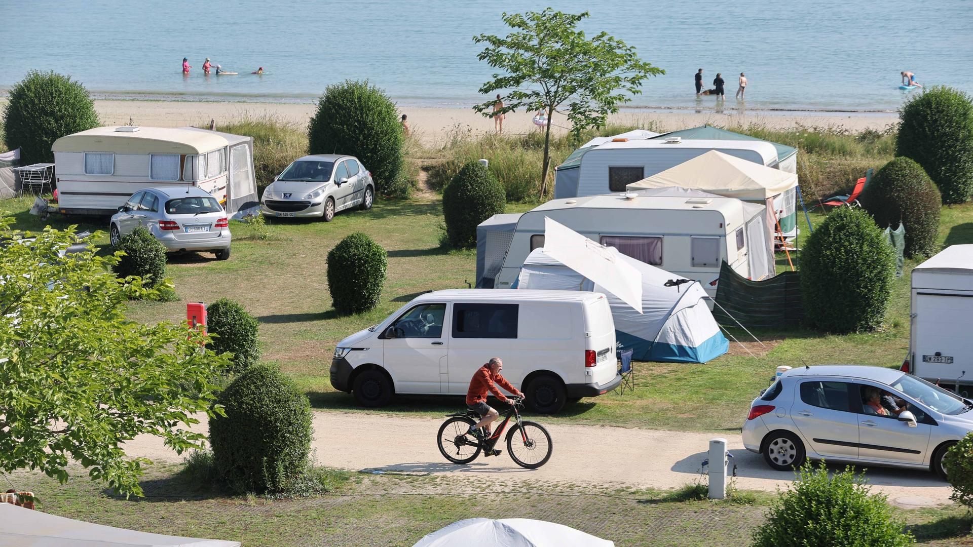 Zu sehen ist ein Campingplatz mit Zelten und Wohnmobilen direkt am Strand. 