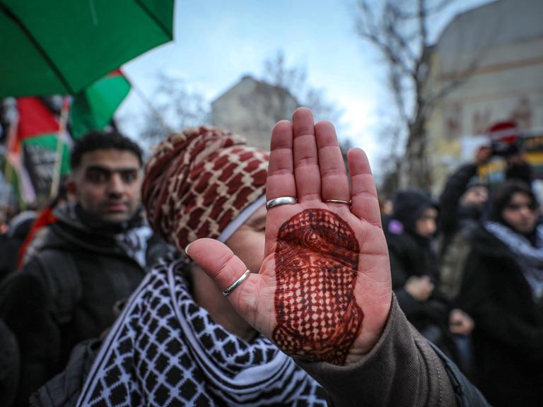 Eine Demonstrantin hält ihre Handfläche in die Kamera, auf die mit Henna das Porträt des toten Hamas-Sprechers Abu Obaida gezeichnet ist. Eine Demonstrantin hält ihre Handfläche in die Kamera, auf die mit Henna das Porträt des toten Hamas-Sprechers Abu Obaida gezeichnet ist.