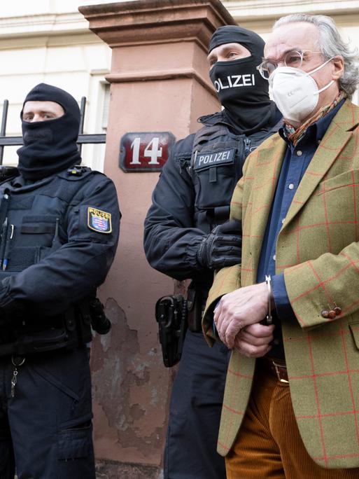Bei einer Razzia gegen mutmaßliche Reichsbürger Ende 2022 führen vermummte Polizisten nach der Durchsuchung eines Hauses Heinrich Prinz Reuß (r.) zu einem Polizeifahrzeug. 