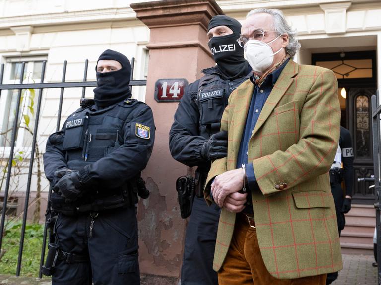 Bei einer Razzia gegen mutmaßliche Reichsbürger Ende 2022 führen vermummte Polizisten nach der Durchsuchung eines Hauses Heinrich Prinz Reuß (r.) zu einem Polizeifahrzeug. 