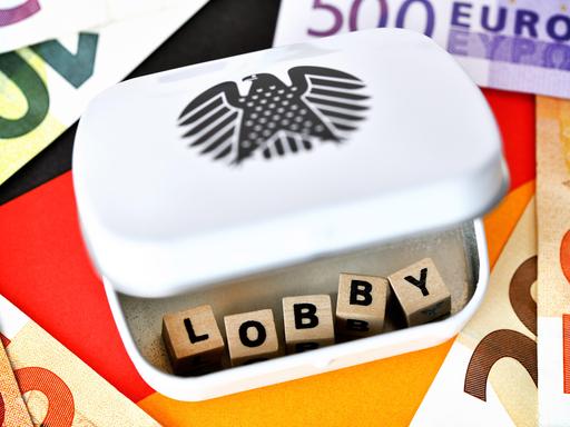 Buchstabenwürfel formen das Wort Lobby in einer Dose mit Bundesadler, Lobbyarbeit