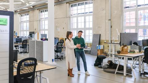 Martin Böhringer, Geschäftsführer und einer der drei Gründer des sächsischen Software-Unternehmens Staffbase, spricht mit Juliane Kiesenbauer, Director Marketing & Communications, am Firmensitz in Chemnitz. Im Hintergrund stehen in einer weitläufigen und hellen ehemaligen Fabriketage Schreibtische.