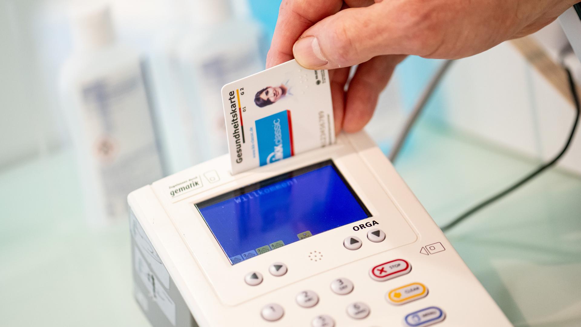 Ein Mitarbeiter einer Apotheke steckt eine Gesundheits-Karte in ein Lese-Gerät. Ein Mitarbeiter einer Apotheke steckt eine Gesundheits-Karte in ein Lese-Gerät.
