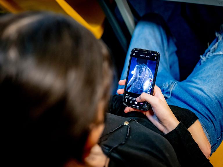 Eine junge Frau schaut auf ihr Mobiltelefon.