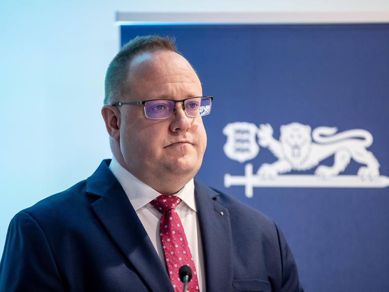 Estlands Geheimdienstchef Kaupo Rosin steht während einer Pressekonferenz in Tallinn 2025 vor einem Aufsteller mit Estlands Wappentier, einem Löwen.