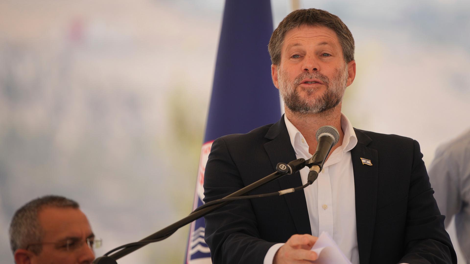 Der israelische Finanzminister Bezalel Smotrich spricht während einer Pressekonferenz, er steht hinter einem Rednerpult und hält Blätter in den Händen. Der israelische Finanzminister Bezalel Smotrich spricht während einer Pressekonferenz, er steht hinter einem Rednerpult und hält Blätter in den Händen.